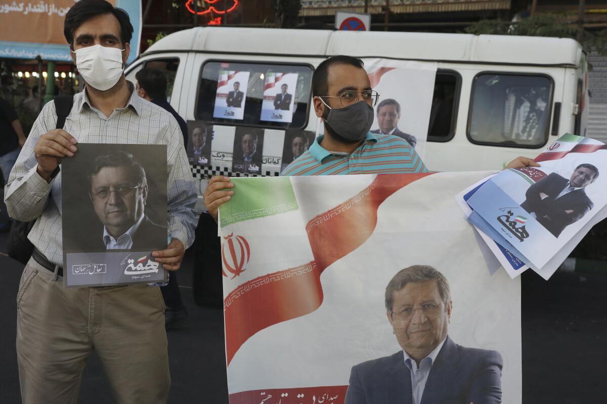 Supporters of Abdolnasser Hemmati, a presidential candidate in the June 18, elections, hold signs with his picture, during a street rally in Tehran, Iran, Tuesday, June 15, 2021. Hemmati, a prominent contender in Iran's presidential election appealed Tuesday for better economic and political relations with the West, his most extensive attempt yet to attract reformist voters just days ahead of the poll. (AP Photo/Vahid Salemi)