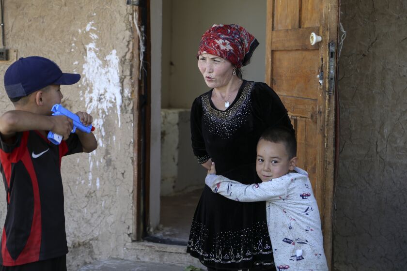 Alif Baqytali hugs his mother, Gulnar Omirzakh, at their new home in Shonzhy, Kazakhstan. Omirzakh, a Chinese-born ethnic Kazakh, says she was forced to get an intrauterine contraceptive device, and that authorities in China threatened to detain her if she didn't pay a large fine for giving birth to Alif, her third child. (AP Photo/Mukhit Toktassyn)