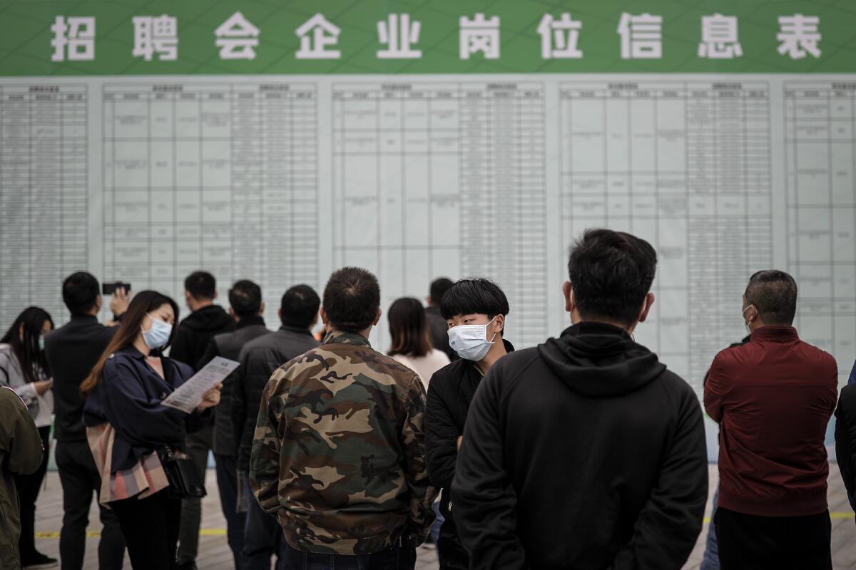 Job applicants read recruitment information at an on-site job fair Tuesday in Wuhan, China.