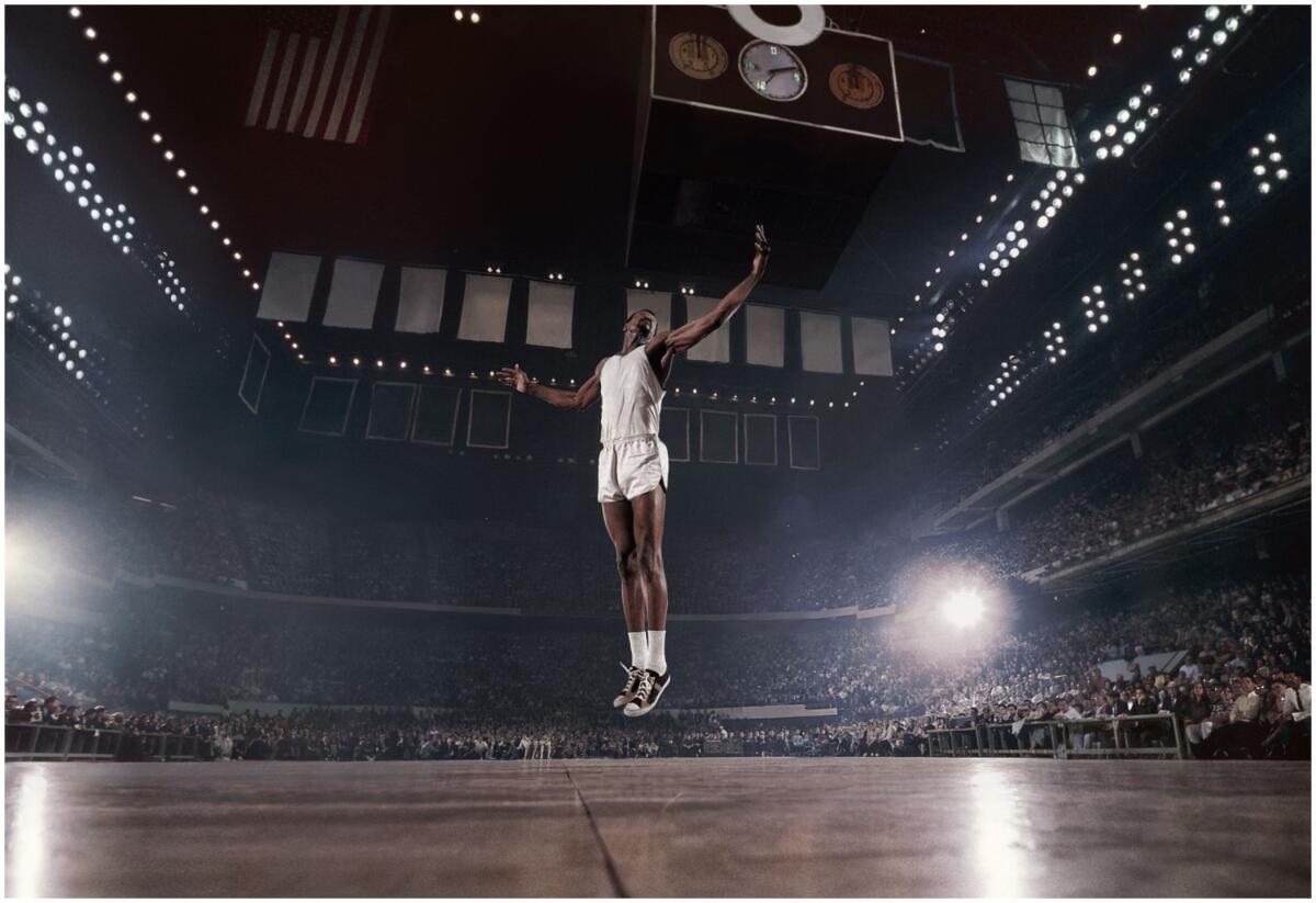 A lone basketball player appears to levitate above the court, surrounded by fans