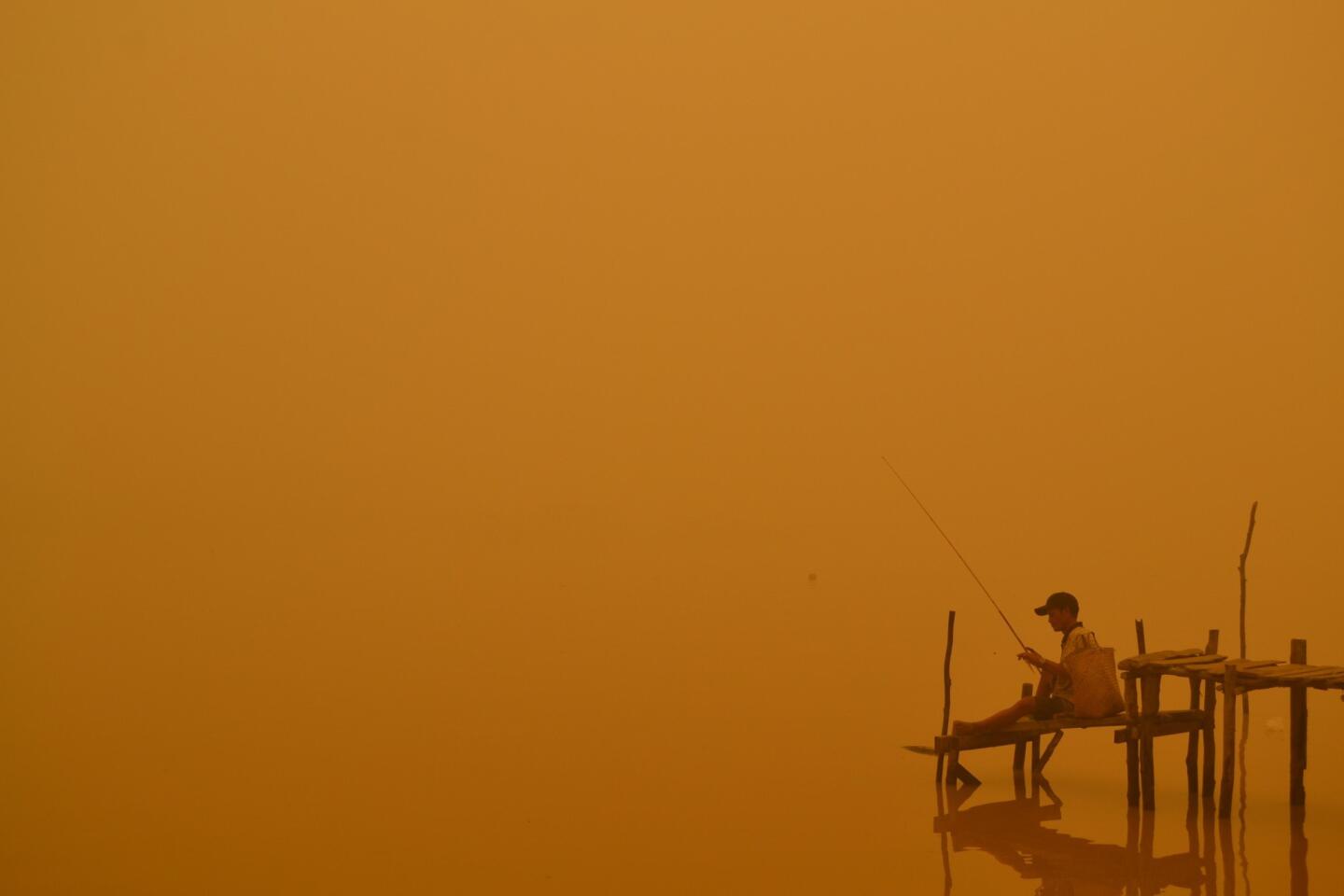 A resident fishes by the river in Palangkaraya city, one of worst-hit by haze in central Kalimantan province. Indonesian forest and agricultural fires are cloaking Southeast Asia in acrid haze.