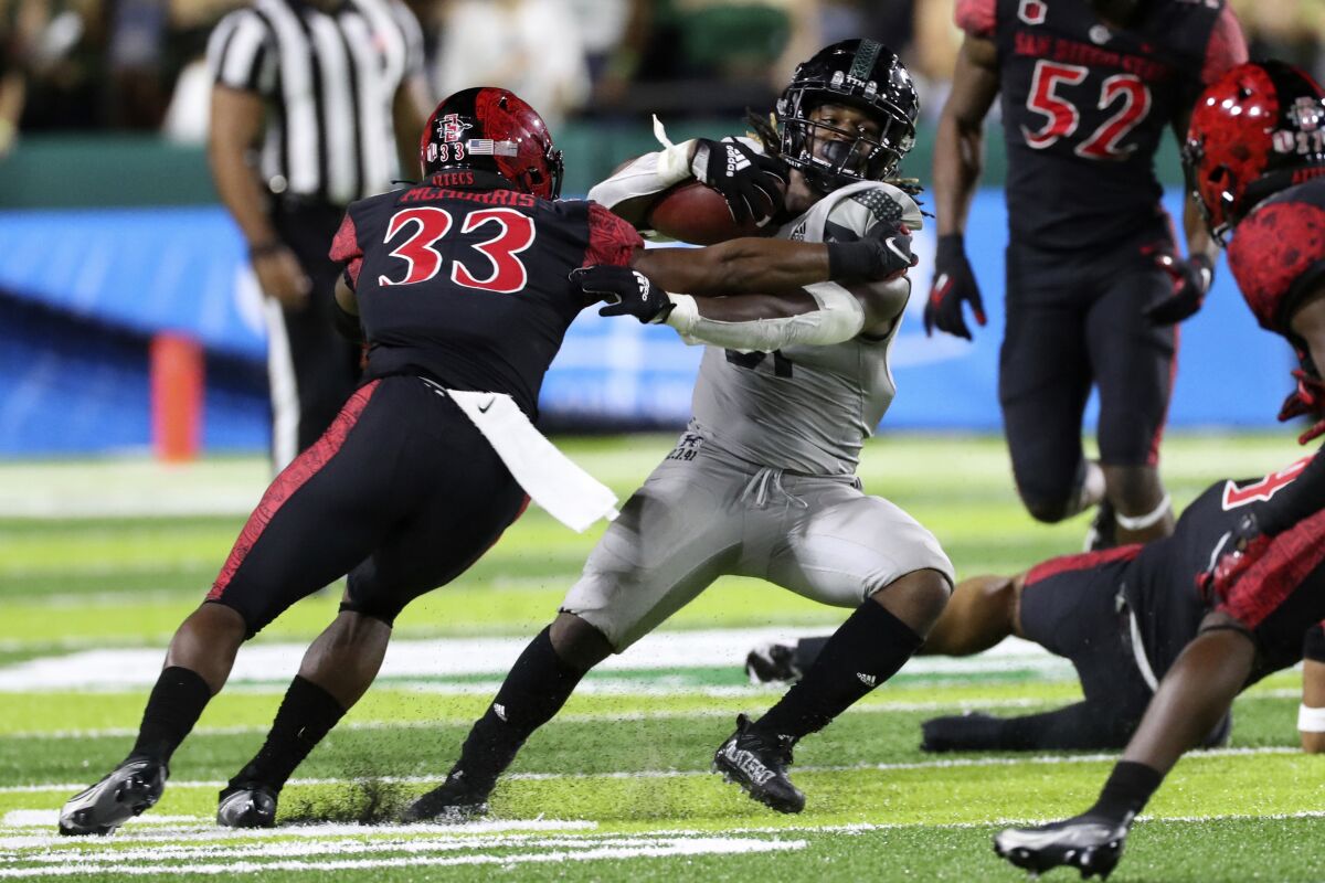 San Diego State safety Patrick McMorris grabs Hawaii running back Dedrick Parson to make a stop.