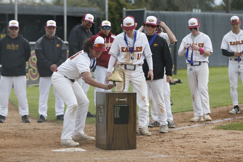Estancia's James De La O (10) rings the bell with teammate John Uchytil (11) after defeating Costa Mesa during Battle of the Bell boys' baseball game on Friday.