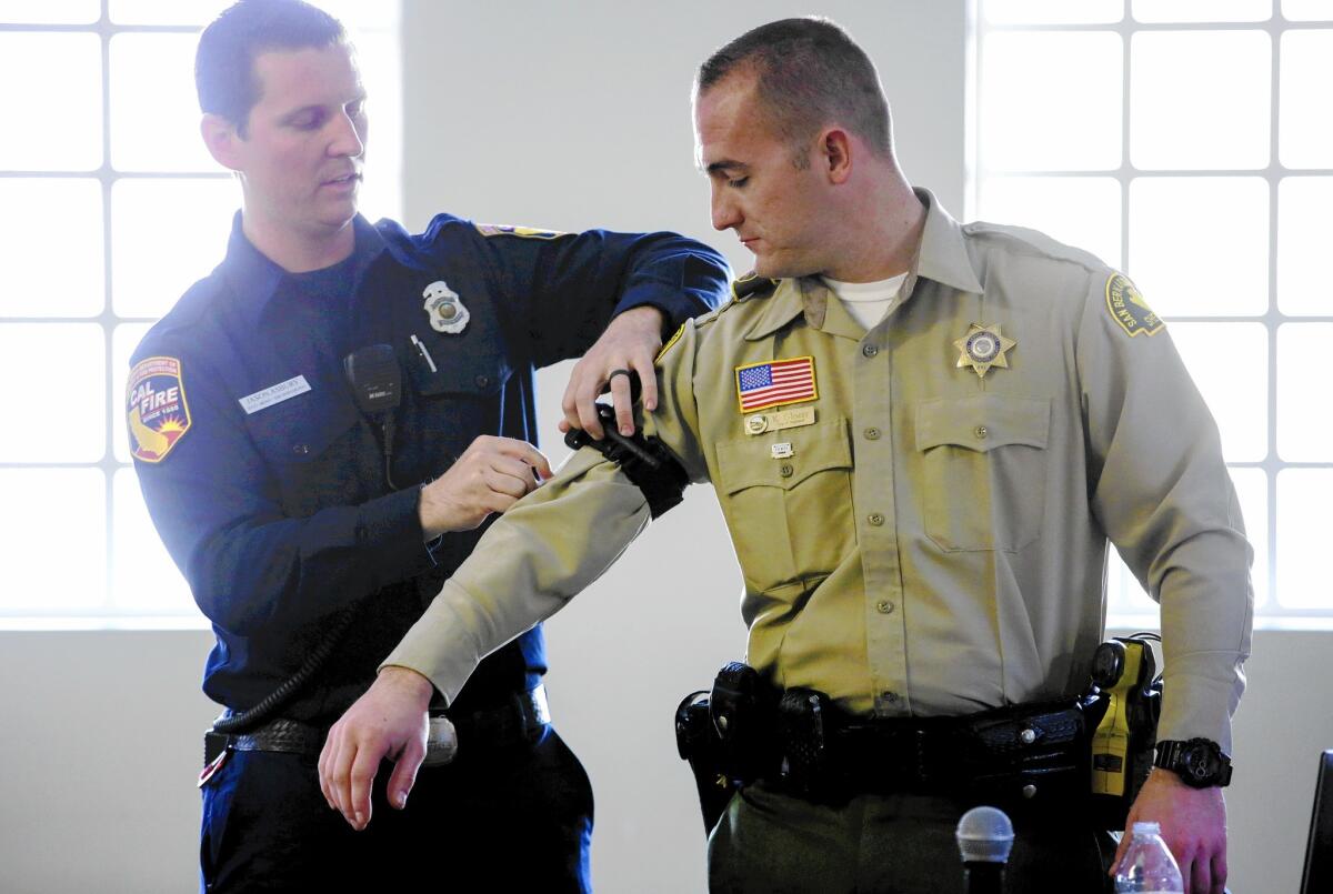 Jason Asbury, left, of the California Department of Forestry and Fire Protection demonstrates on San Bernardino County Sheriff's Deputy Kyle Glozer how to apply a tourniquet to stop major bleeding.