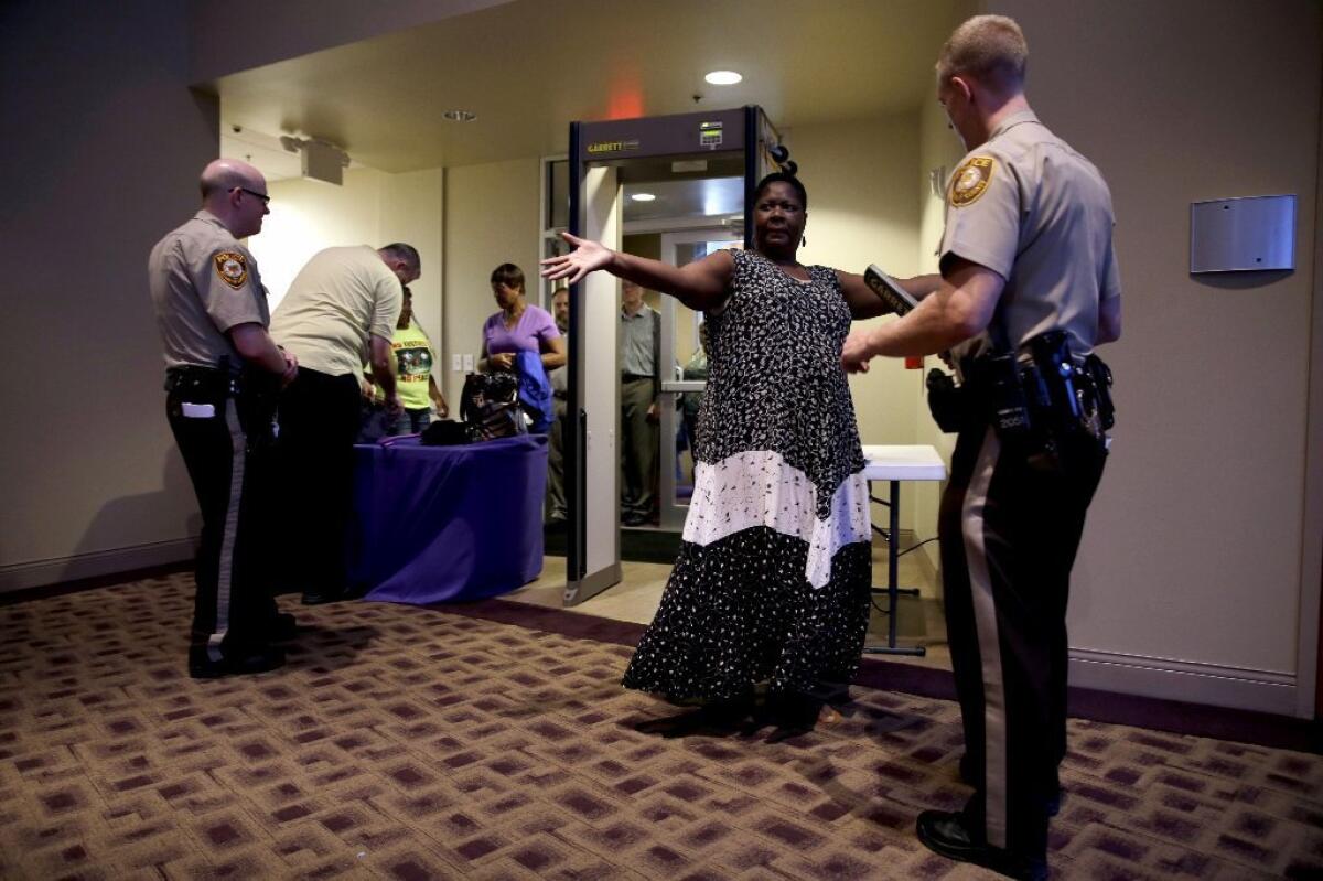 Patricia Cowan holds out her arms for a St. Louis County police officer as she and others are searched as they enter Greater Grace Church before the start of a meeting of the Ferguson City Council.
