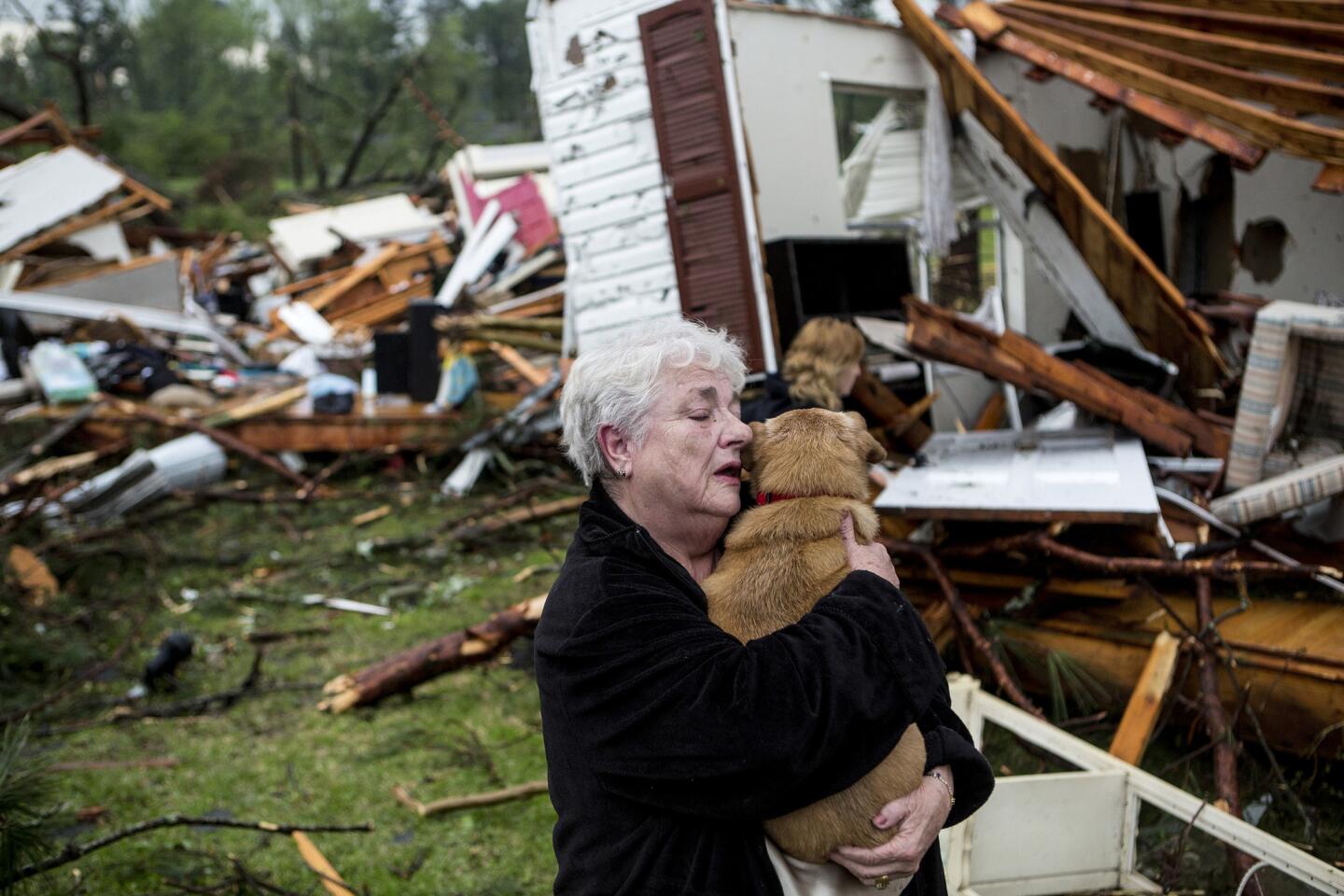 Constance Lambert embraces her dog after finding it alive when returning to her destroyed home in Tupelo, Miss.