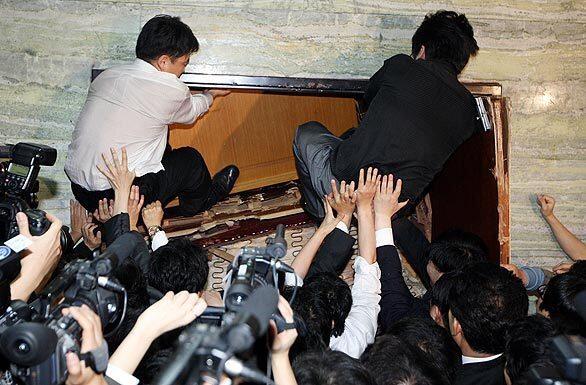 South Korean opposition party members try to break into a parliamentary committee room where the ruling Grand National Party was preparing to introduce a bill to ratify a trade pact with Washington. Scuffles and violence are not uncommon among South Korean legislators.