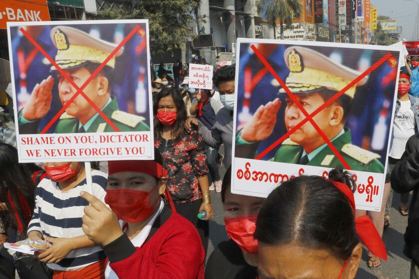 Protesters hold placards with an X mark on the image of Myanmar Commander-in-Chief Senior General Min Aung Hlaing and a sign that says 'Shame on You, Dictator. We never forgive you' as they march in Mandalay, Myanmar on Monday, Feb. 8, 2021. A protest against Myanmar's one-week-old military government swelled rapidly Monday morning as opposition to the coup grew increasingly bold. (AP Photo)