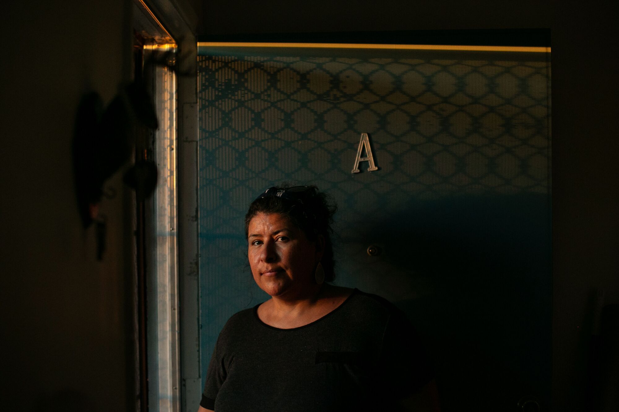 Luz Puebla stands in the doorway of her apartment