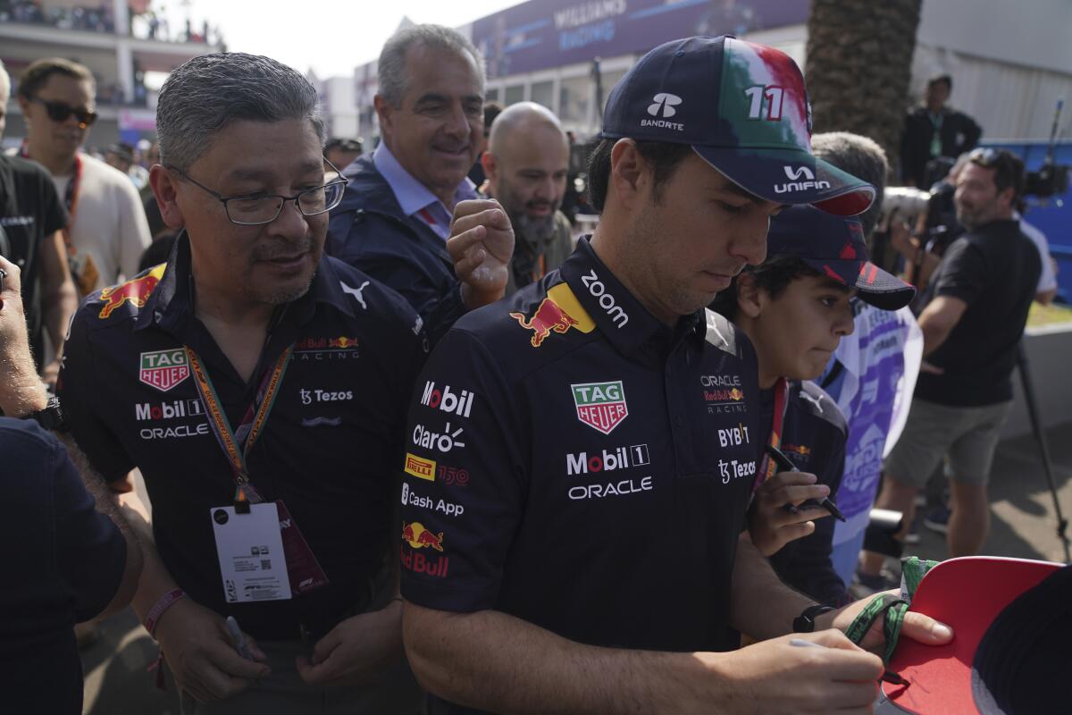 Red Bull driver Sergio Perez, of Mexico, signs an autograph during the Formula One Mexico Grand Prix
