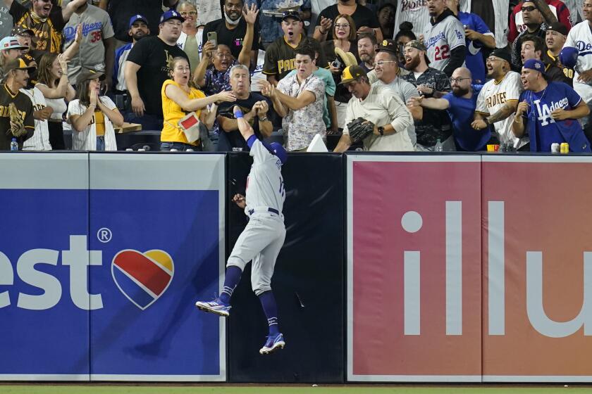 Los Angeles Dodgers left fielder AJ Pollock makes the catch at the wall, competing against spectators the the ball, for the out on San Diego Padres' Manny Machado during the fourth inning of a baseball game Tuesday, Aug. 24, 2021, in San Diego. (AP Photo/Gregory Bull)