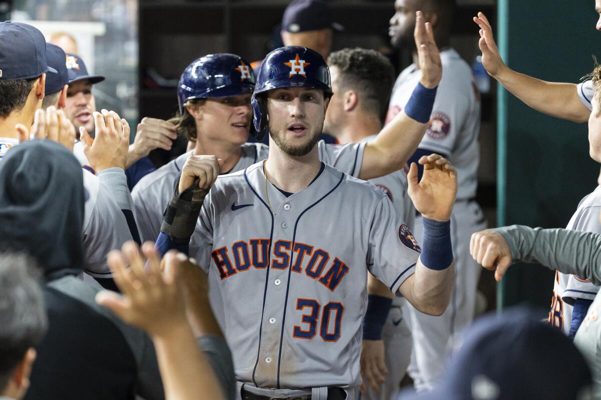 Houston Astros' Kyle Tucker (30) is congratulated by teammates after scoring a run during the seventh inning of a baseball game against the Texas Rangers, Friday, Aug. 27, 2021, in Arlington, Texas. (AP Photo/Sam Hodde)