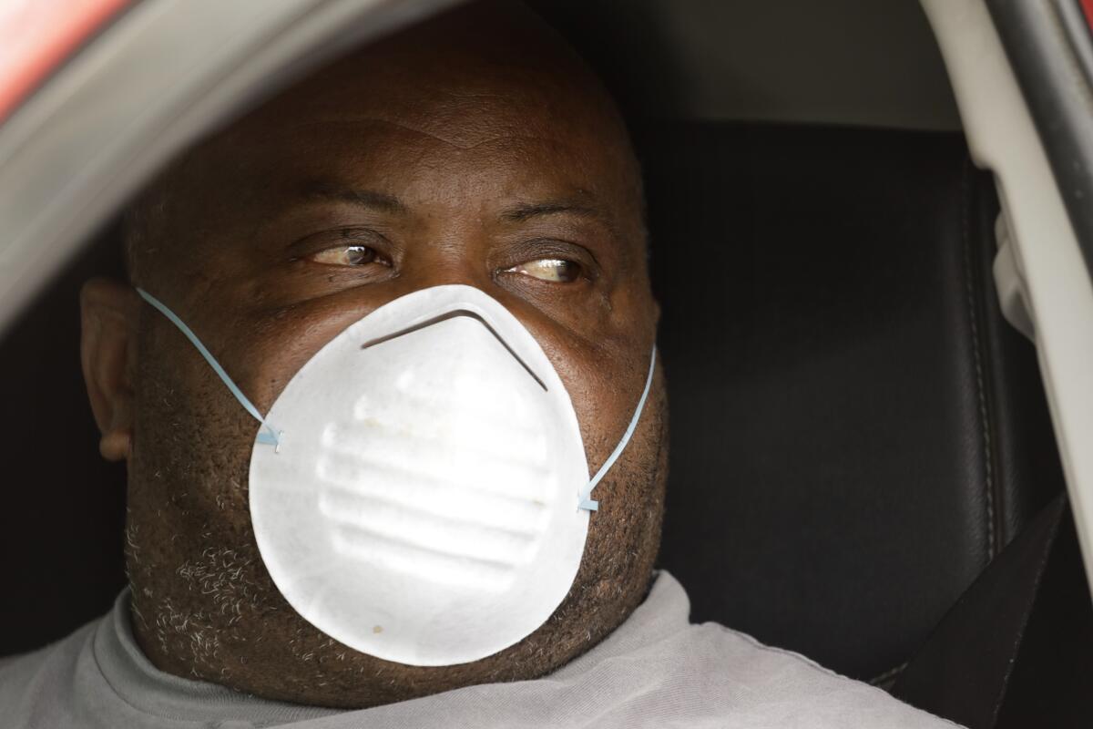 Everett Bradford sits in his car to attend a funeral in Madera, Calif., for Wanda DeSelle, who died of COVID-19.