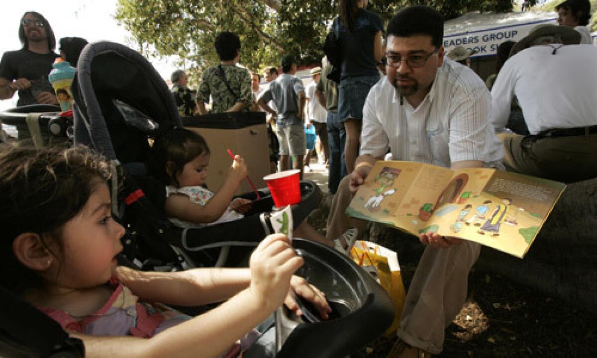 Gerardo Campos, right, reads, "Picadillo the Armadillo," book to his daughter Angelina, 3, left, and niece Omega Flores, 1, during the Los Angeles Times Festival of Books in 2008.