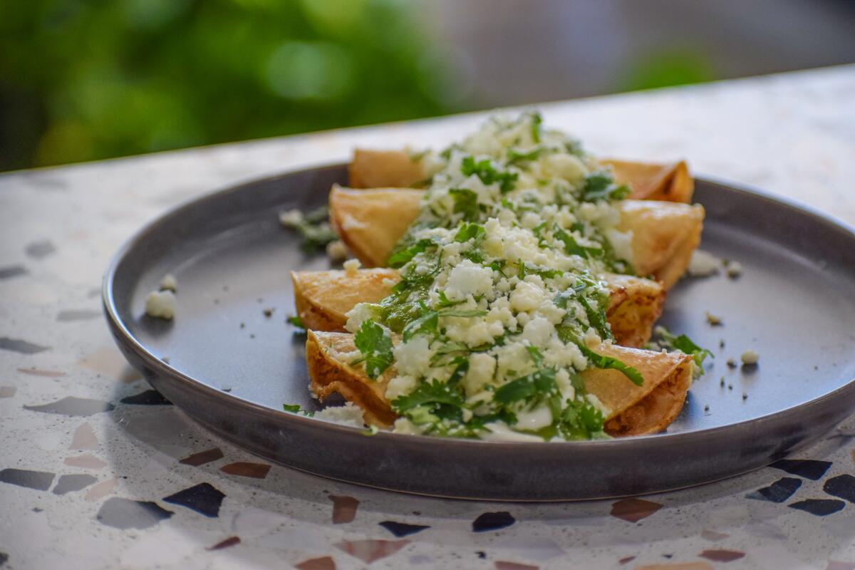 A plate holds four tacos topped with queso fresco.