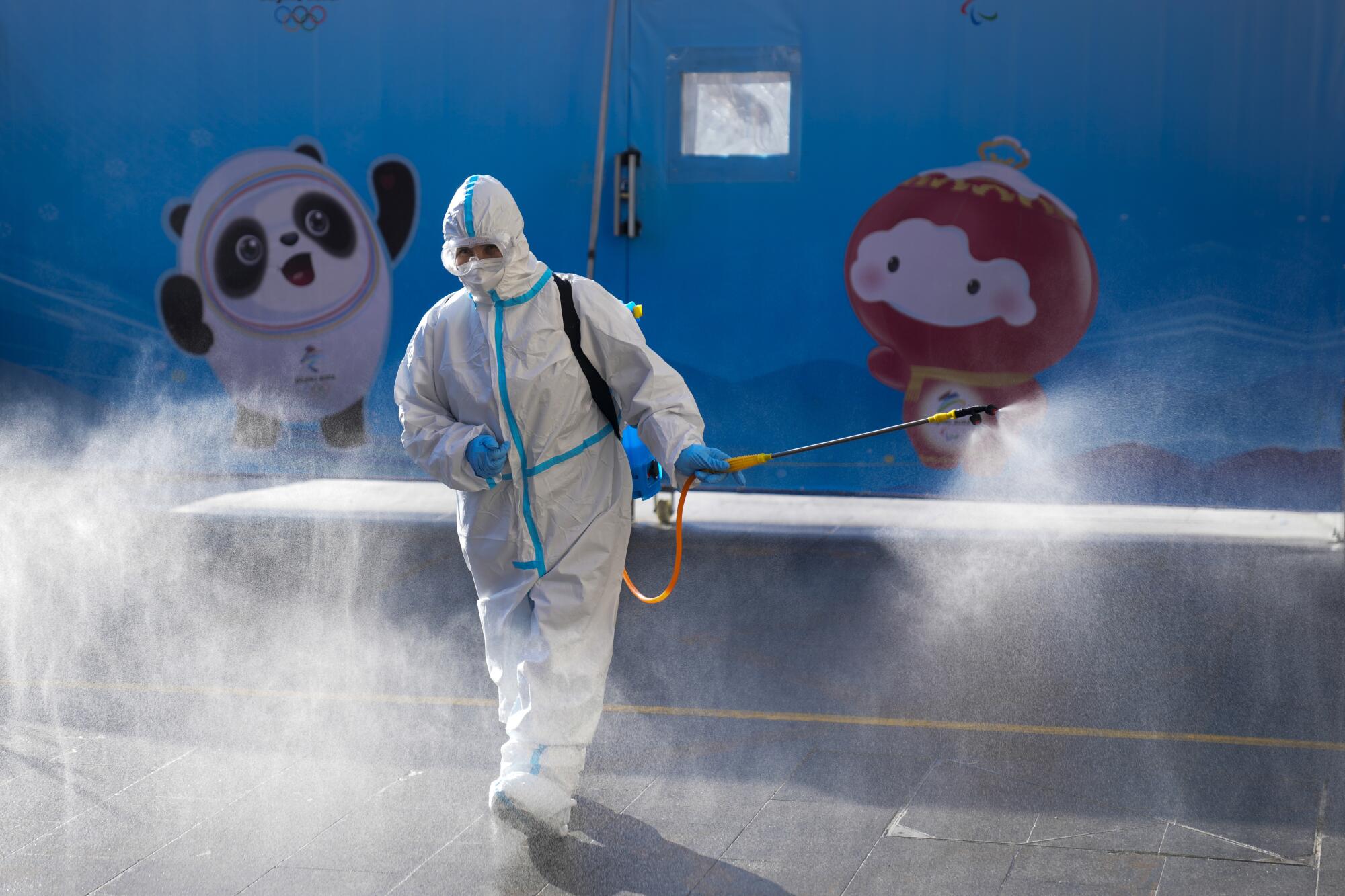 A worker wearing a protective suit sprays disinfectant outside a hotel in Beijing.