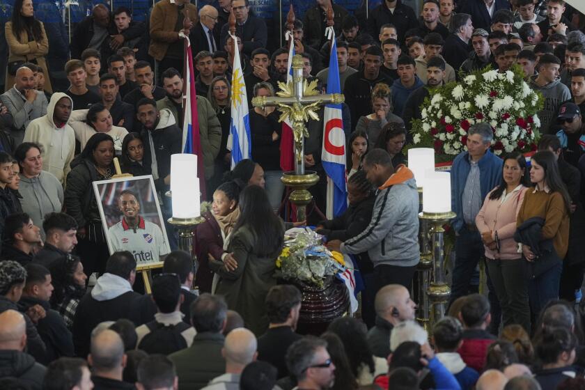 Familiares y aficionados del fútbol observan el velatorio de Juan Izquierdo en Montevideo, el jueves 29 de agosto de 2024. El jugador del club uruguayo Nacional falleció tras sufrir una arritmia en un partido de la Copa Libertadores en Sao Paulo. (AP Foto/ Matilde Campodónico) Family members and fans of soccer player Juan Izquierdo gather around his coffin during a wake at his Nacional soccer club in Montevideo, Uruguay, Thursday, Aug. 29, 2024. Izquierdo died at a Brazilian hospital after collapsing on Aug. 22 during a Copa Libertadores soccer match between Nacional and Sao Paulo. (AP Photo/Matilde Campodonico)