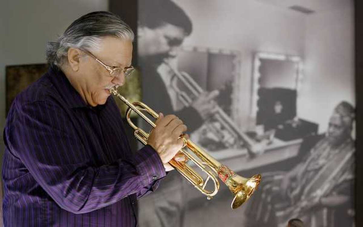Trumpet master Arturo Sandoval at his home in Tarzana. Sandoval is standing near a portrait of himself in his 20's with Dizzy Gillespie. He's been playing trumpet for 53 years.