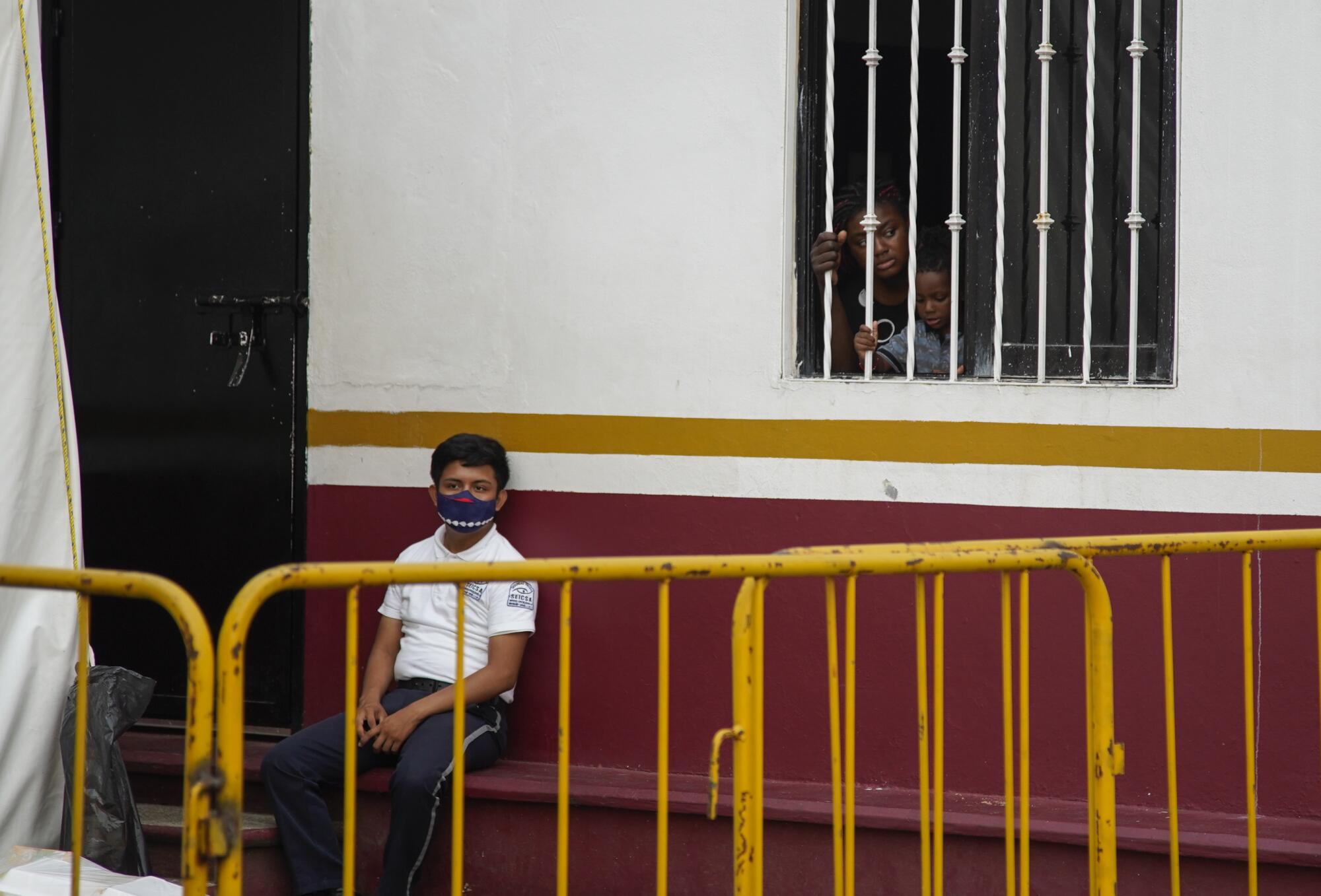 A woman and child in Mexican immigration custody look out a window of a detention center
