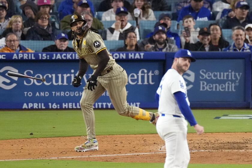 San Diego Padres' Fernando Tatis Jr., left, heads to first after hitting a two-run home run as Los Angeles Dodgers pitcher Ryan Brasier watches during the seventh inning of a baseball game Friday, April 12, 2024, in Los Angeles. (AP Photo/Mark J. Terrill)