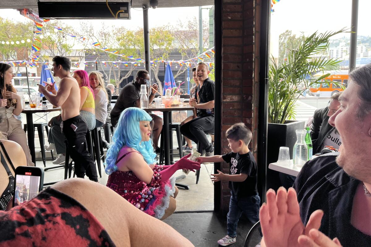 Toddler hands a queen a tip at drag brunch at Rocco's
