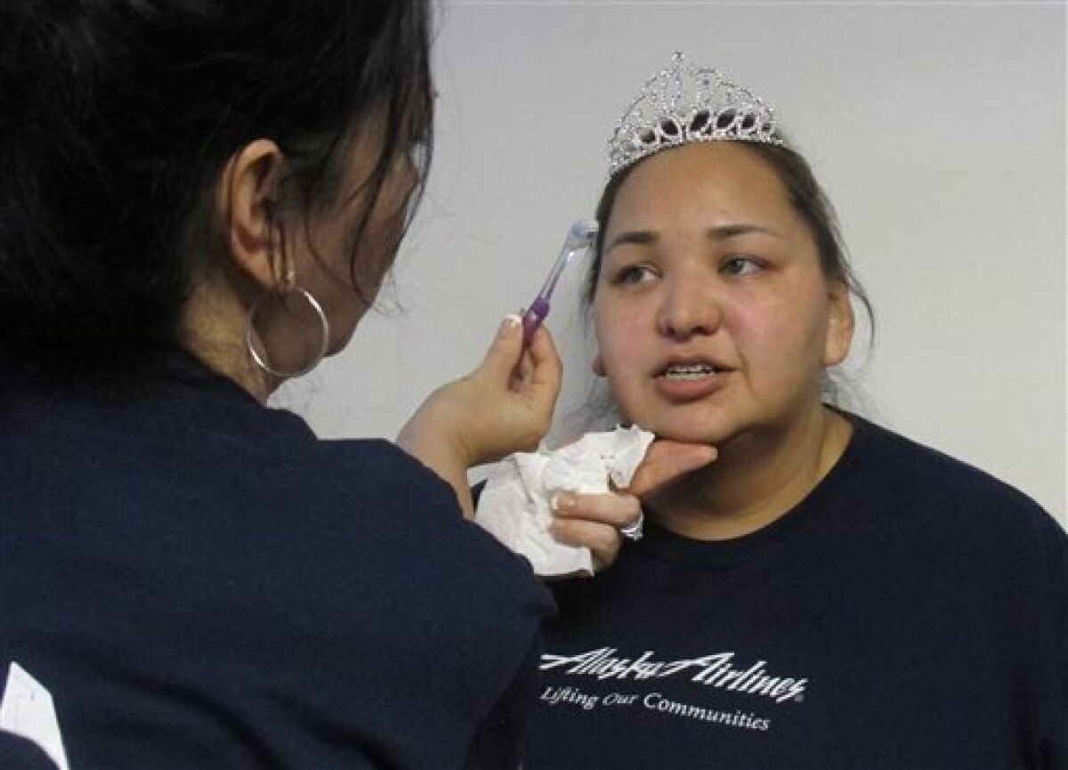 In this photo taken March 30, 2013, in Sitka, Alaska, a volunteer applies makeup to Terri Bogren, a Seattle woman who started the Prom Princess program, which helps get students at Mount Edgecumbe High School get ready for the prom. Mount Edgecumbe is Alaska's only boarding school, and many of the 360 students who attended prom come from more than a hundred Alaska villages. Employees and retirees of Seattle-based Alaska Airlines are in the fifth year of securing donated dresses and bringing in