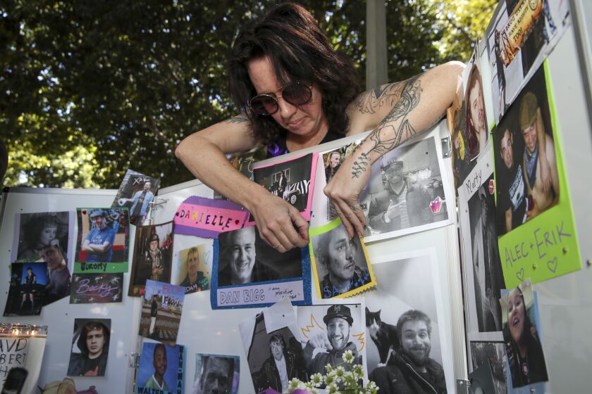 Los Angeles, CA - August 31: Shannon Knox, 38, places the photos overdose victims at a makeshift memorial on International Overdose Awareness Day outside City Hall on Wednesday, Aug. 31, 2022 in Los Angeles, CA. (Irfan Khan / Los Angeles Times)