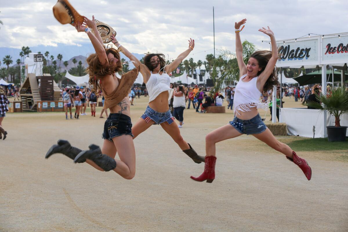 Three women wearing cowboy boots jump in the air