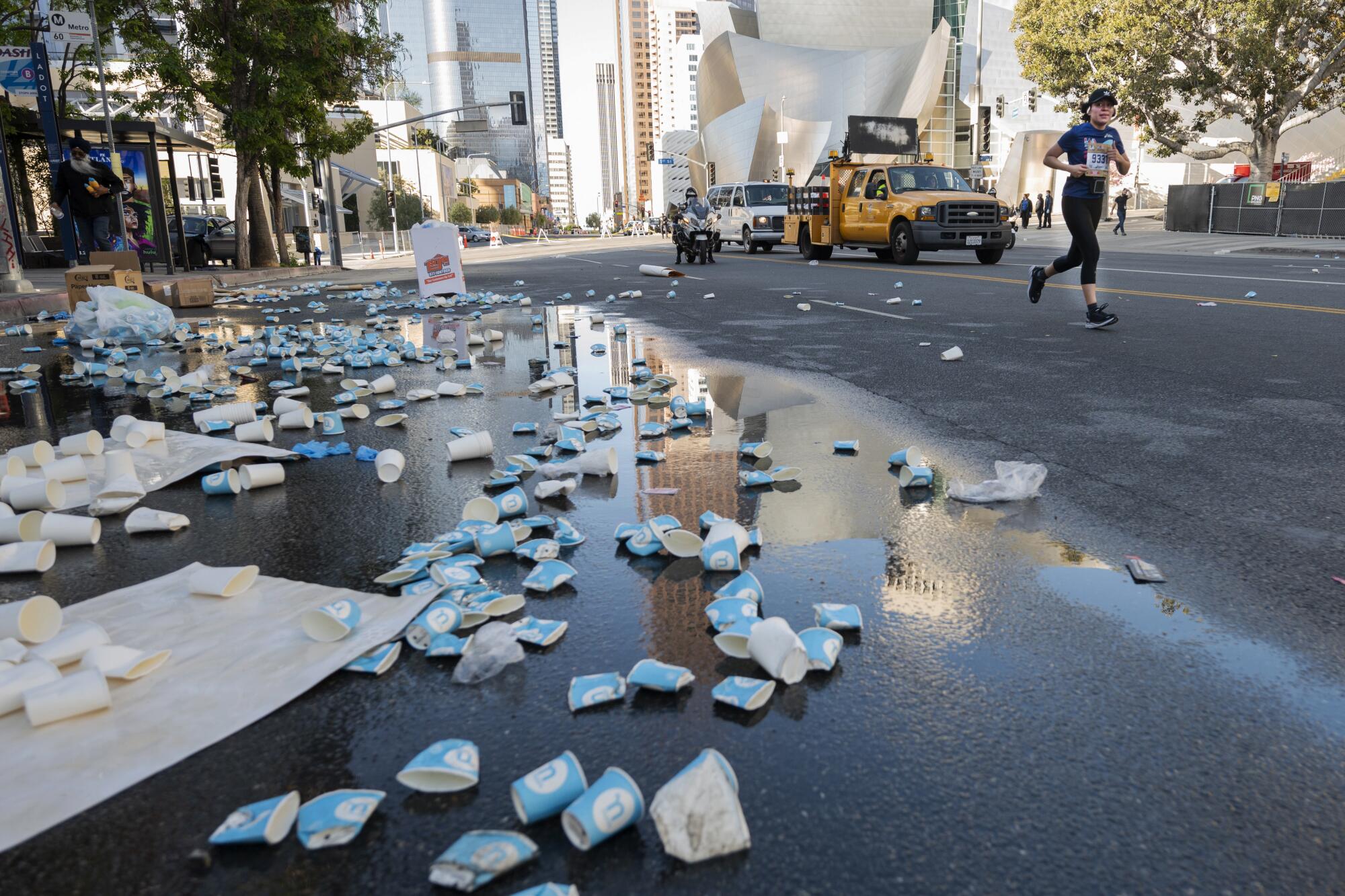 A runner jogs by tossed water cups during the 37th annual Los Angeles Marathon in Los Angeles.