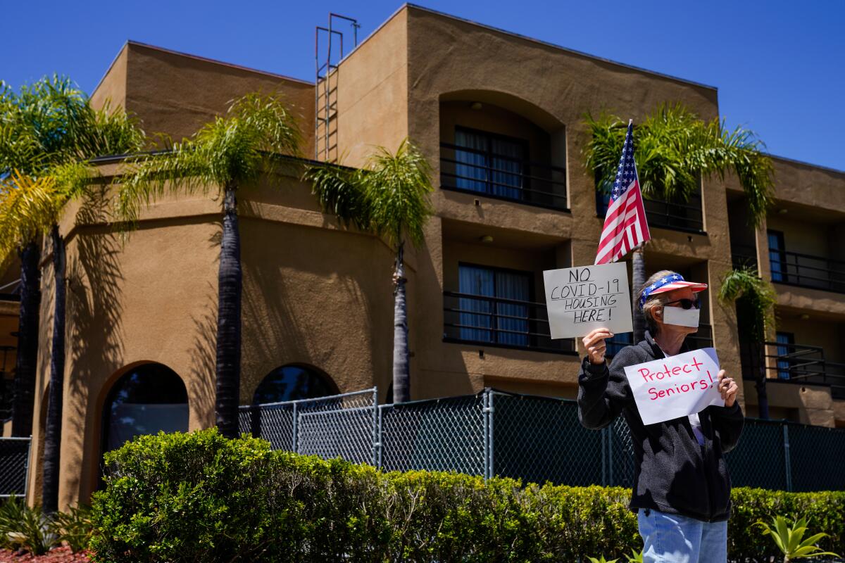 Protester Karen Litfin of Laguna Hills stands outside the Laguna Hills Inn, which the county is planning to use to house homeless people with the coronavirus.