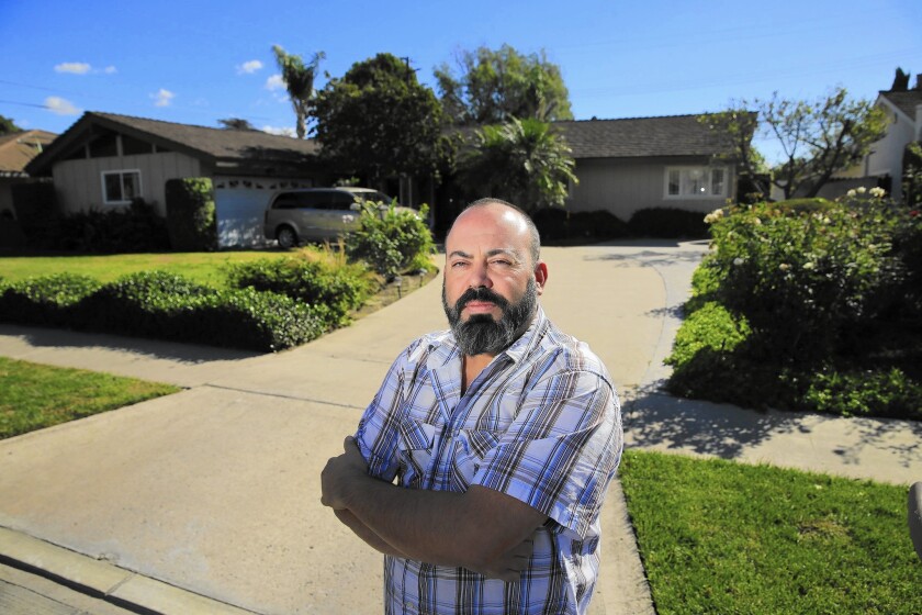 Fred Cornejo of Anaheim stands in front of one of seven homes near his that were converted to short-term rentals. They are “totally destroying the neighborhood,” he says.