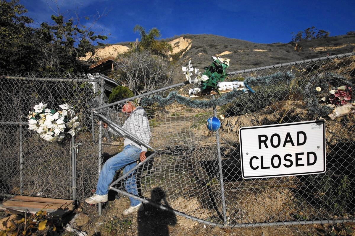 La Conchita resident Ernie Garcia makes his way through a hole in a chain-link fence amid damage from the 2005 mudslide.