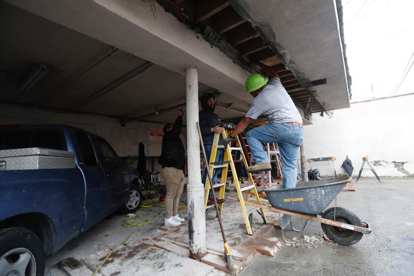 Kehl Tonga, right, a superintendent with Cal-quake construction, works with other crew members in a 2 story apartment building at 5833 Gregory Ave in Los Angeles undergoing an earthquake retrofit.