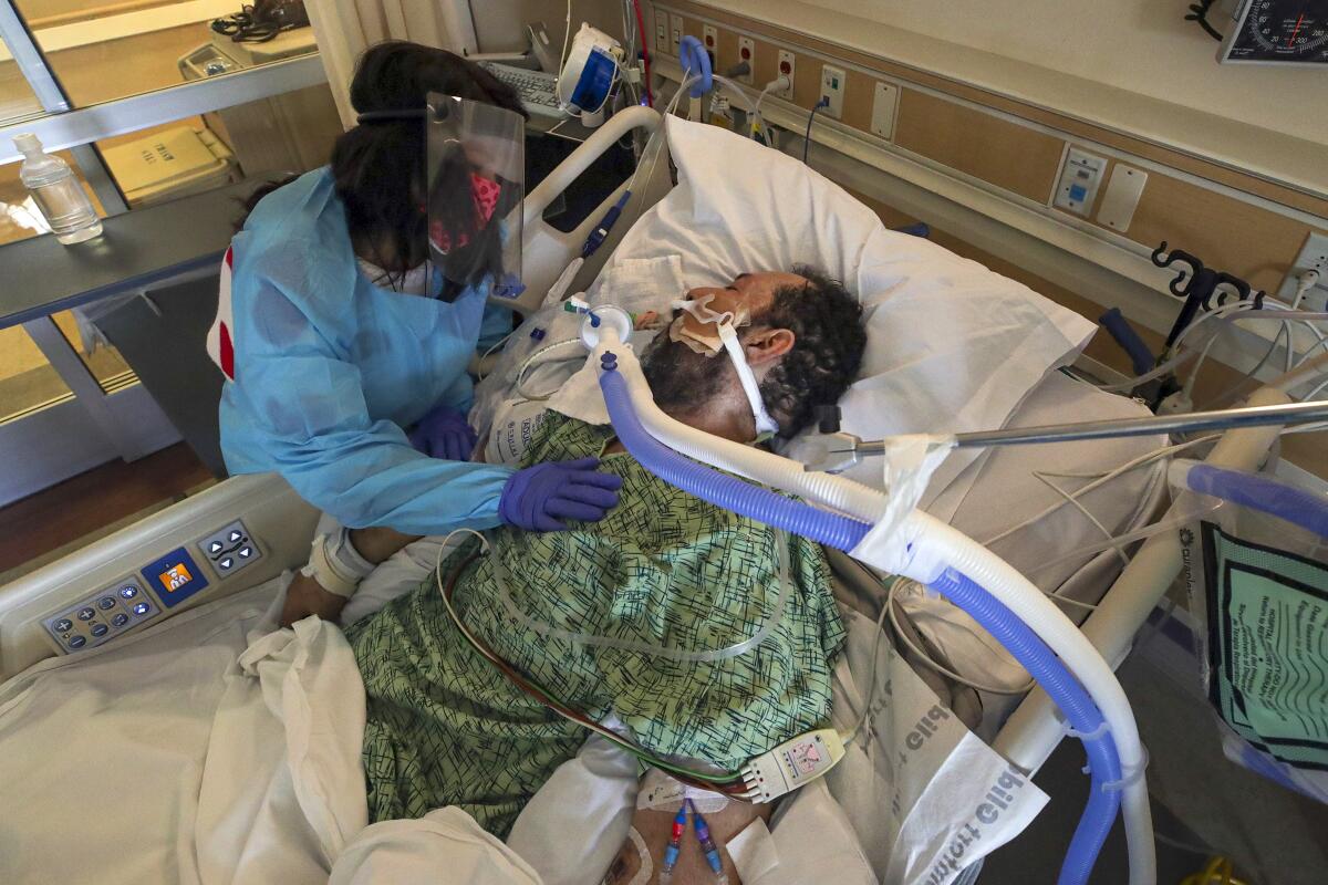 A man on a ventilator and a woman in personal protective equipment.
