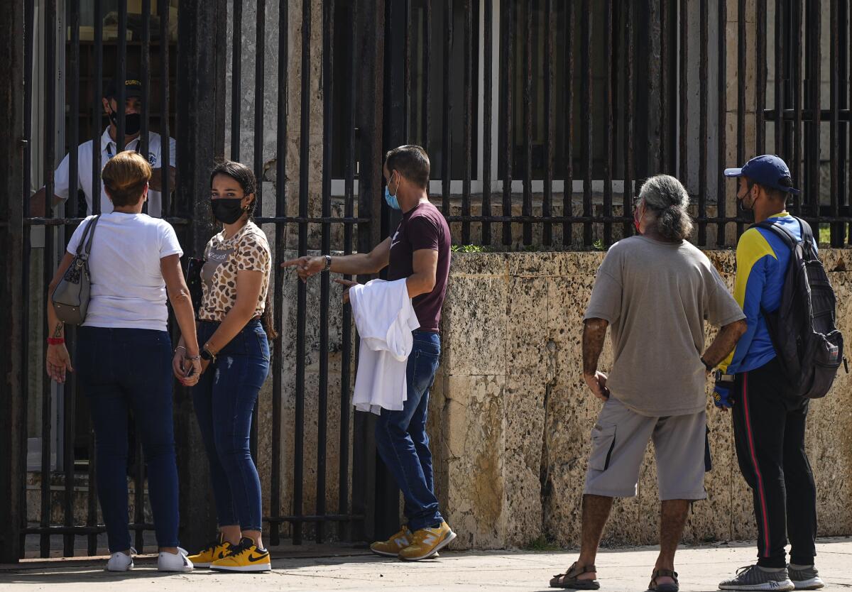 People wait their turns outside the U.S. embassy the day after it reopened its consular services in Havana, Cuba.