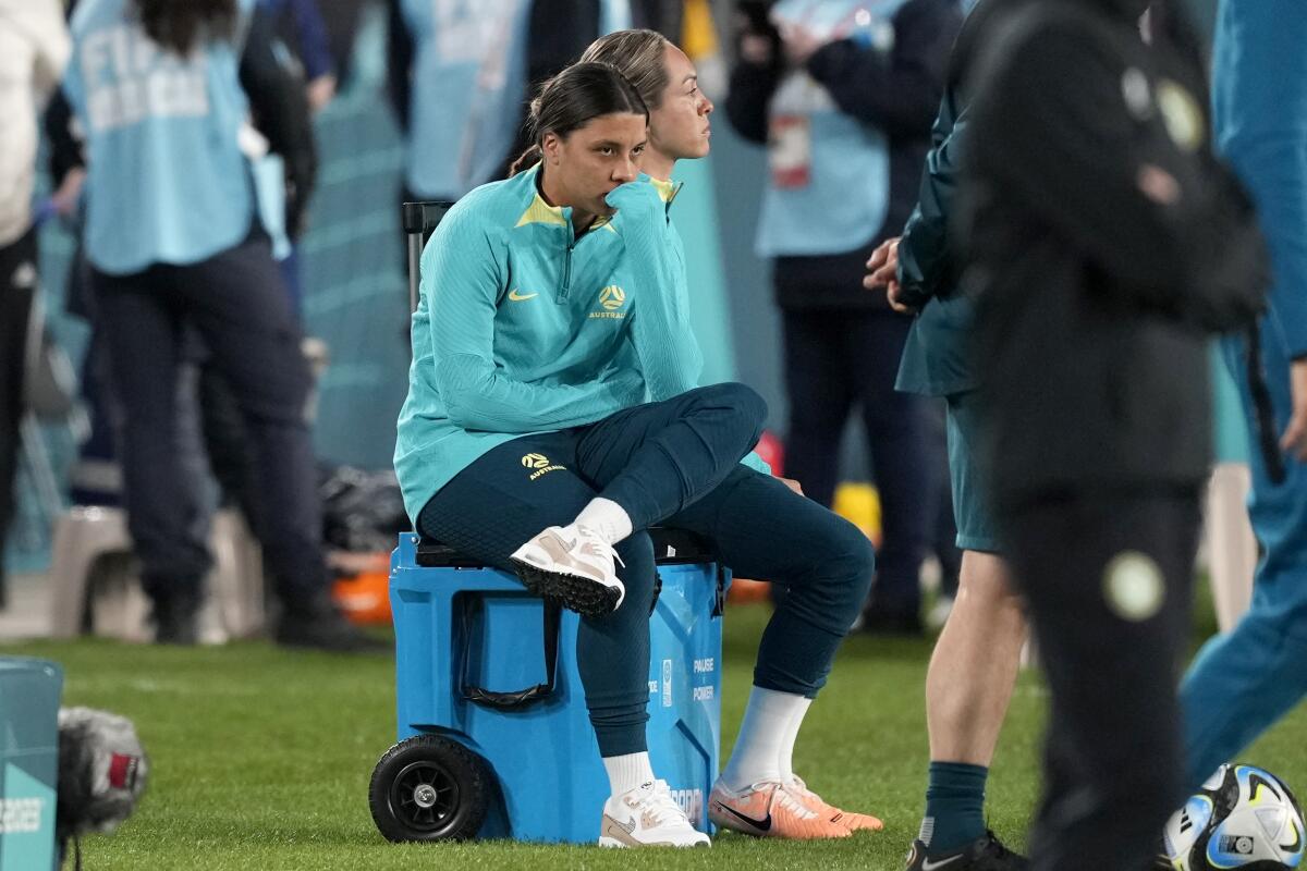 Australia's Sam Kerr sits on a cooler and watches her teammates warm up before facing Ireland in the World Cup 
