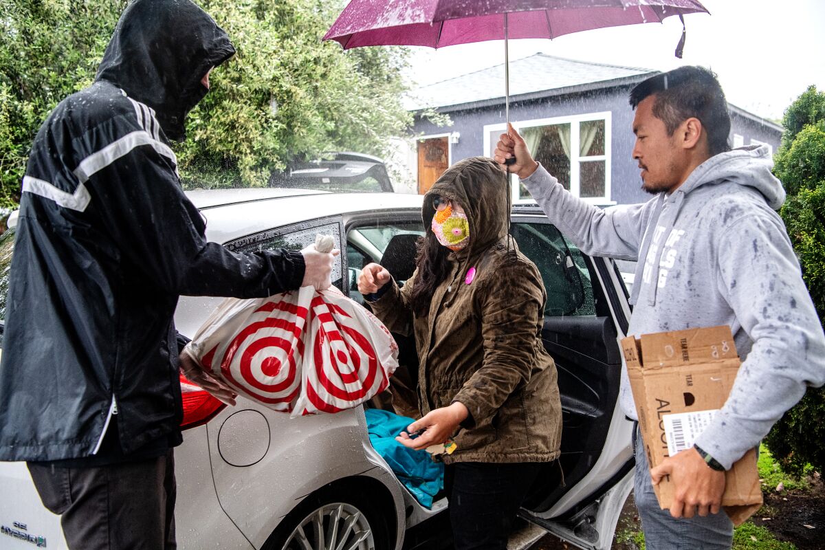 People pack bagged food and supplies into the back seat of a car.