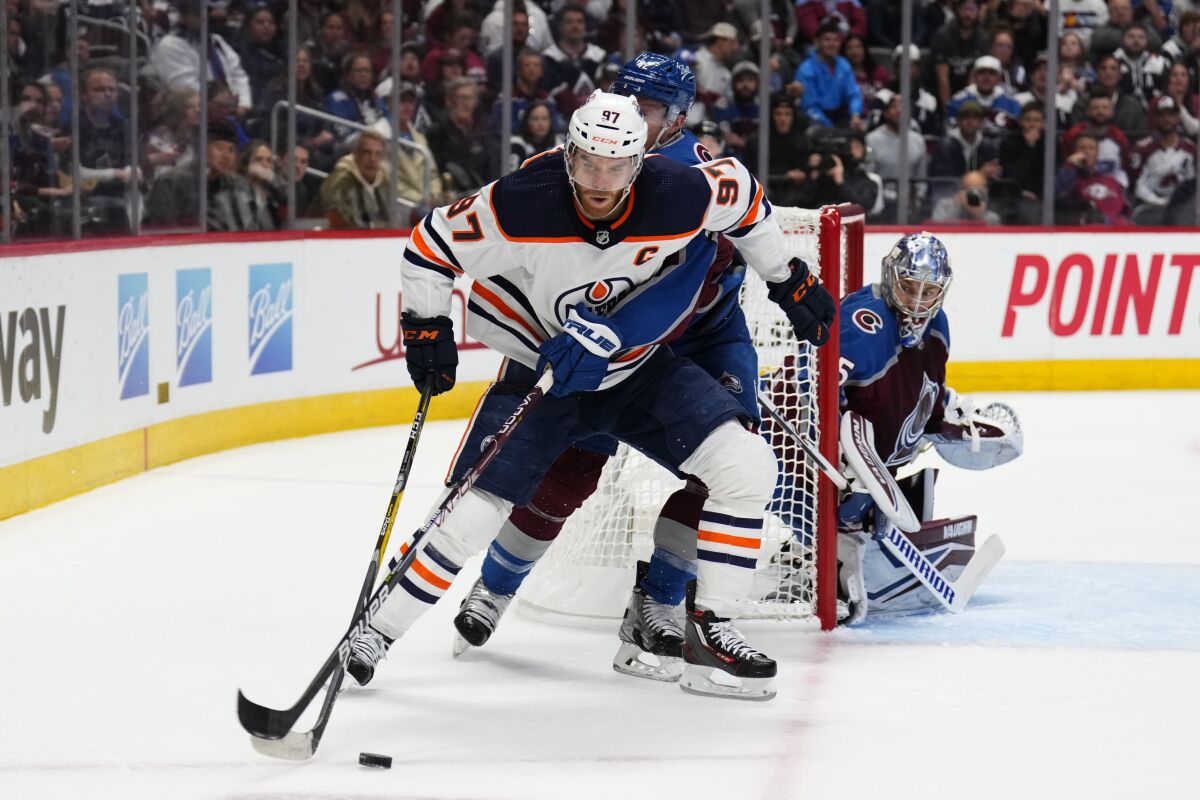 Edmonton Oilers center Connor McDavid is pressured by Colorado Avalanche defenseman Josh Manson.