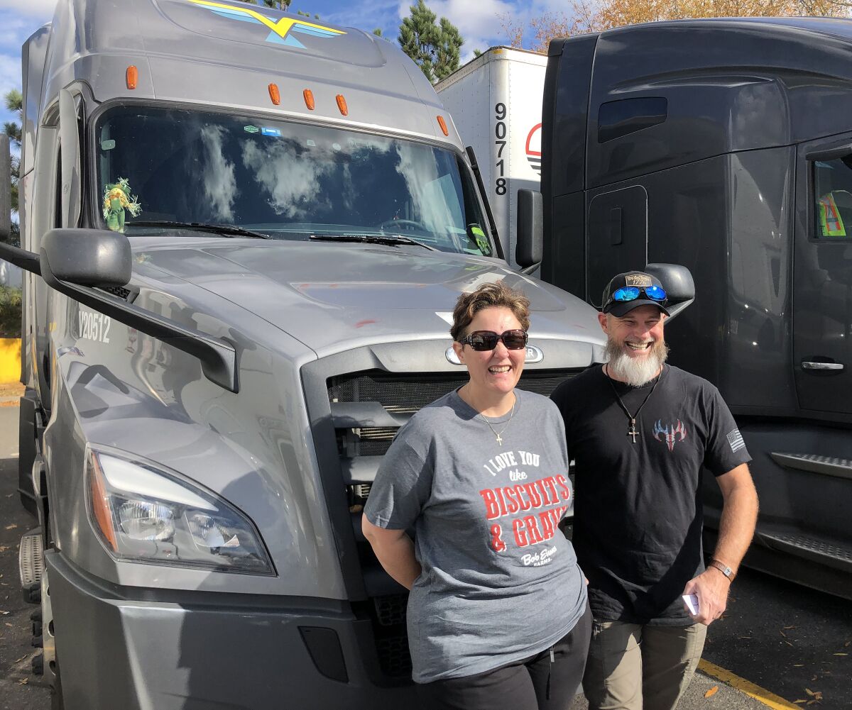 Brian Bielli stands next to his wife in front of a truck.