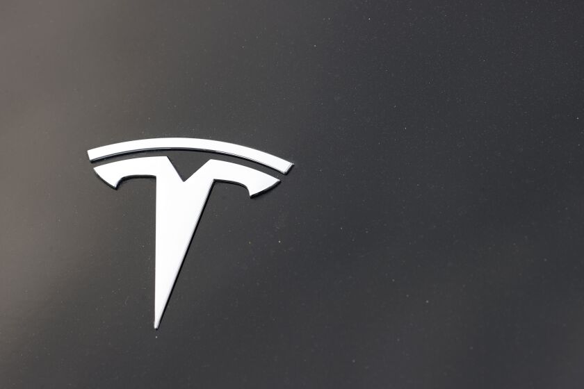 FILE - The Tesla company logo is seen on the hood of an unsold vehicle at a dealership on Aug. 9, 2020, in Littleton, Colo. In a report released Wednesday, Feb. 8, 2023, investigators from the National Transportation Safety Board apparently solved the mystery of why no one was found behind the wheel of a Tesla that crashed in Texas two years ago, killing two men. During the April 2021 crash in Spring, Texas, the driver apparently moved to the back seat after slamming into the car's front air bag, deforming the steering wheel in the crash. (AP Photo/David Zalubowski, File)