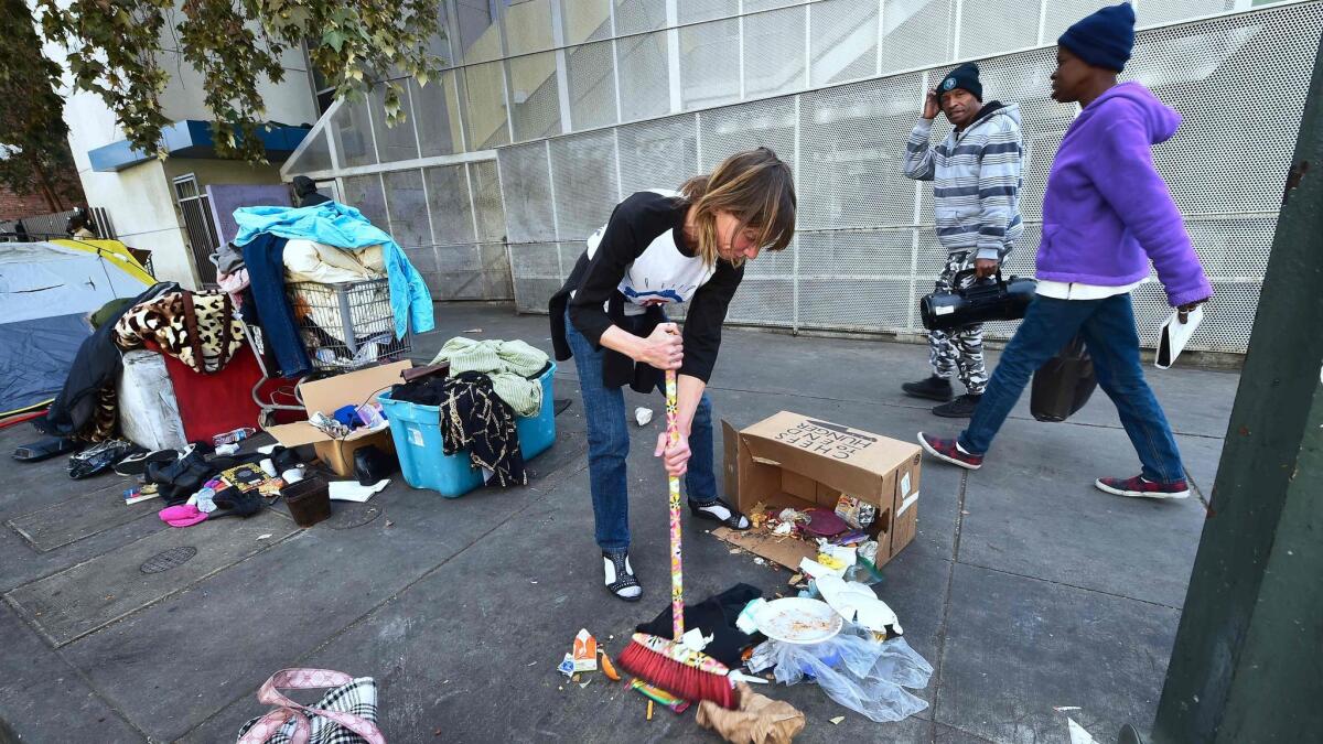 A homeless woman sweeps her spot on skid row in downtown Los Angeles.