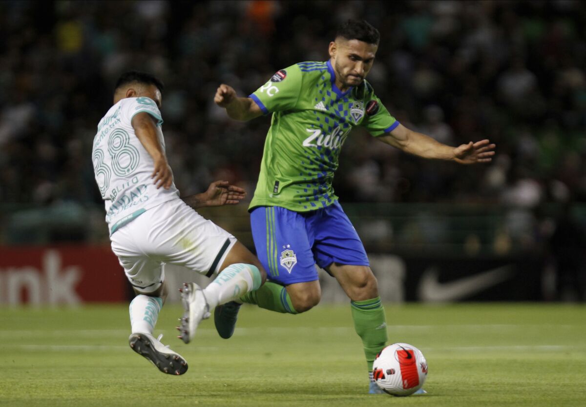 Cristian Roldan of the Seattle Sounders, right, and Juan Rangel of Mexico's Leon fight for the ball during a CONCACAF Champions League soccer match in Leon, Mexico, Thursday, March 17, 2022. (AP Photo/Mario Armas)