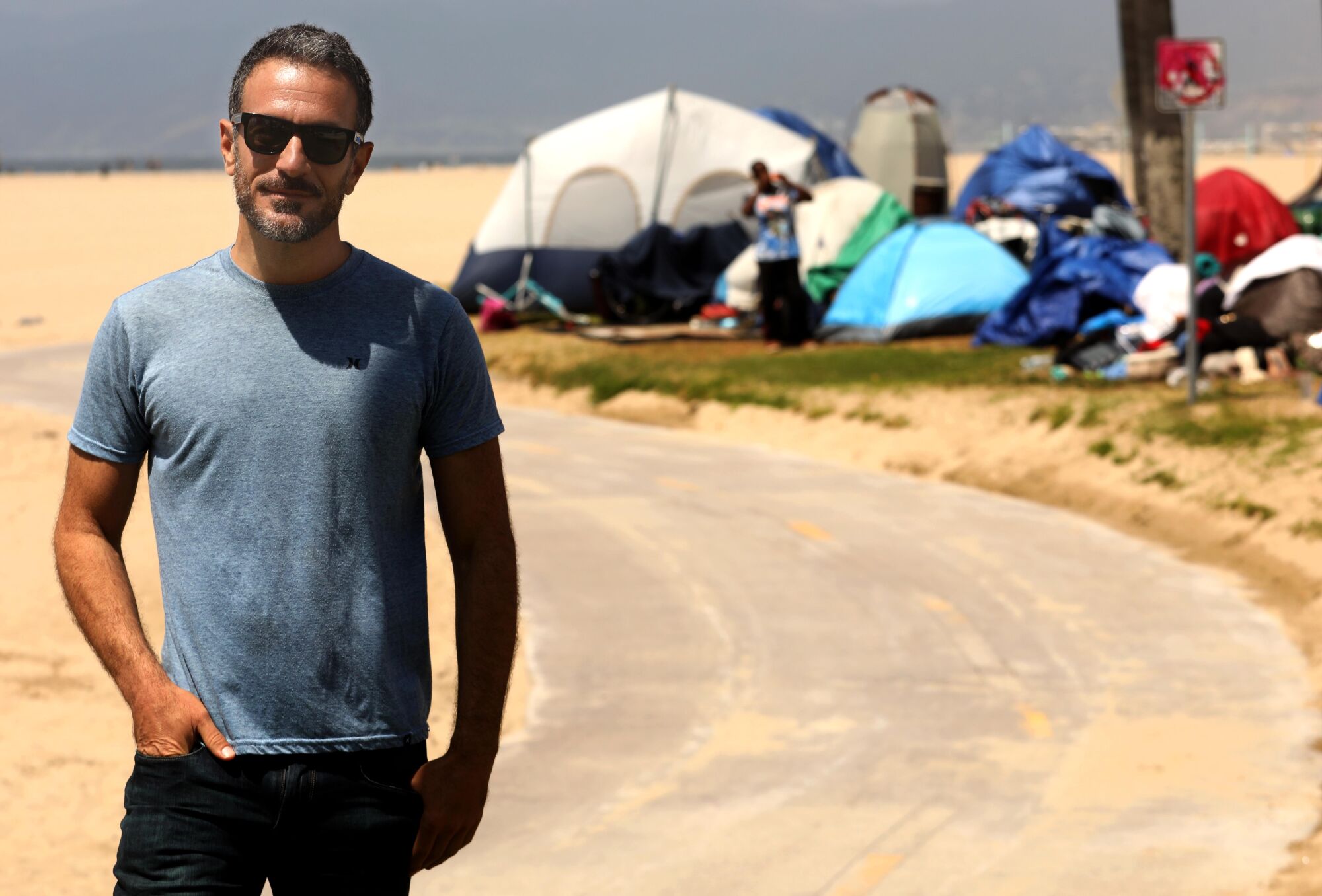 Brian Averill stands in front of a homeless camp