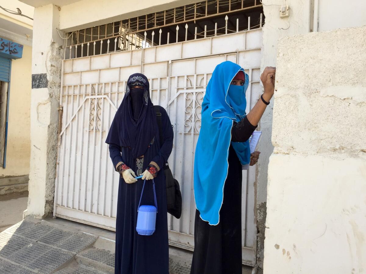 Polio workers write in chalk outside a house to indicate the vaccination status of those inside in Karachi, Pakistan. (Shashank Bengali / Los Angeles Times)