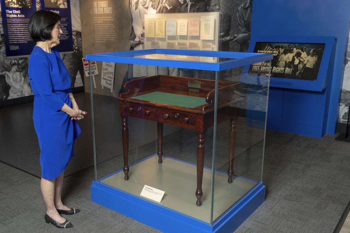 A person stands next to a desk in a glass case.