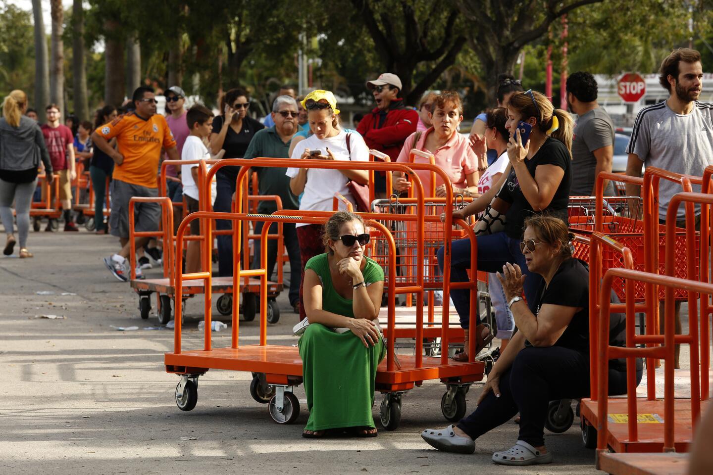 Rita Peummel, green dress, and hundreds of others wait in line Sept. 8, 2017, at Home Depot in Miami to get supplies to board up their homes ahead of Hurricane Irma. Police were on the scene to keep things orderly.