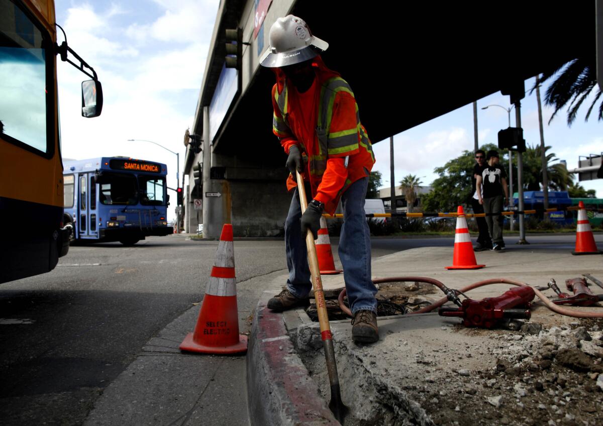 A construction worker cleans out a trench on a roadway project at Los Angeles International Airport. The White House has proposed a budget that increases passenger fees to raise funding for airport improvement projects.