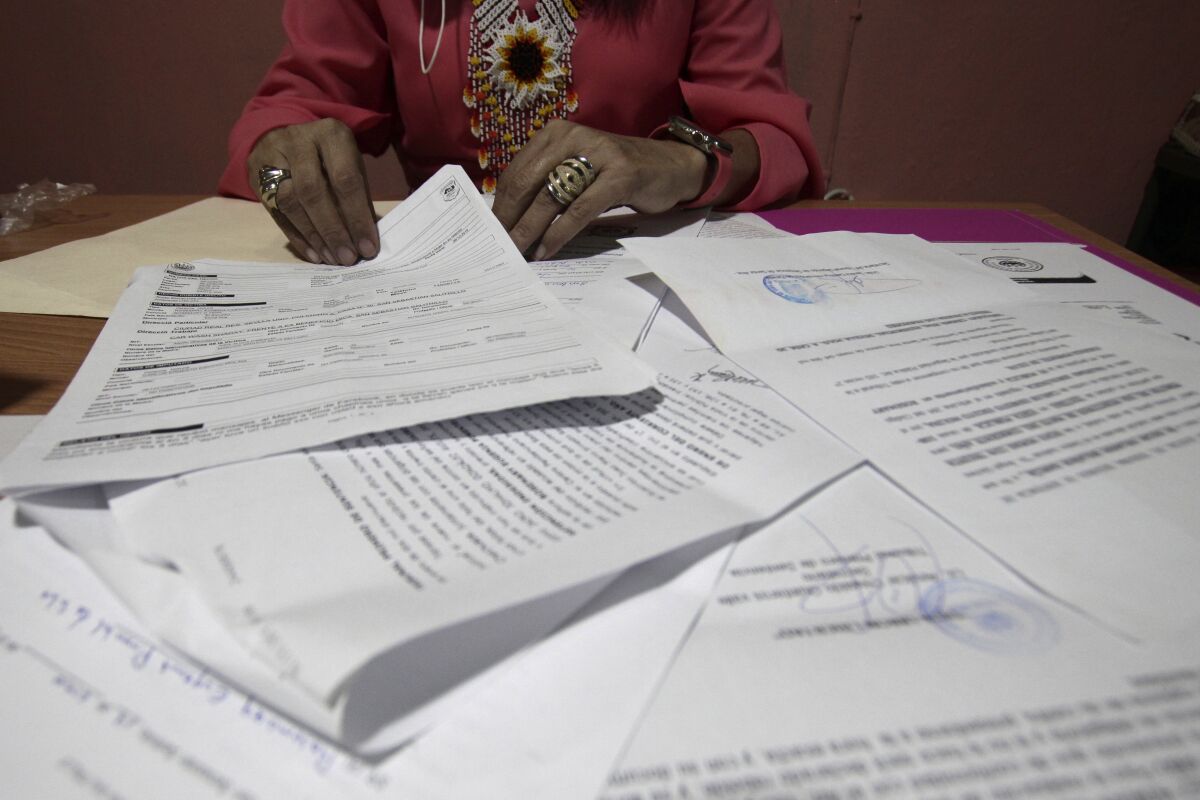 A Salvadoran businesswoman, who is one of the applicants of a small refugee program that was shut down by President Donald Trump, shows documents of the many times she has reported robberies and extortions, in Santa Ana, El Salvador, Saturday, Aug. 22, 2020. She said she was terrified when she began receiving death threats in 2013. Men with tattoos would come to a car wash she used to own to demand "monthly compensation" for letting her operate. She says she has received many threats since — through calls, text messages and social media. (AP Photo/Salvador Melendez)