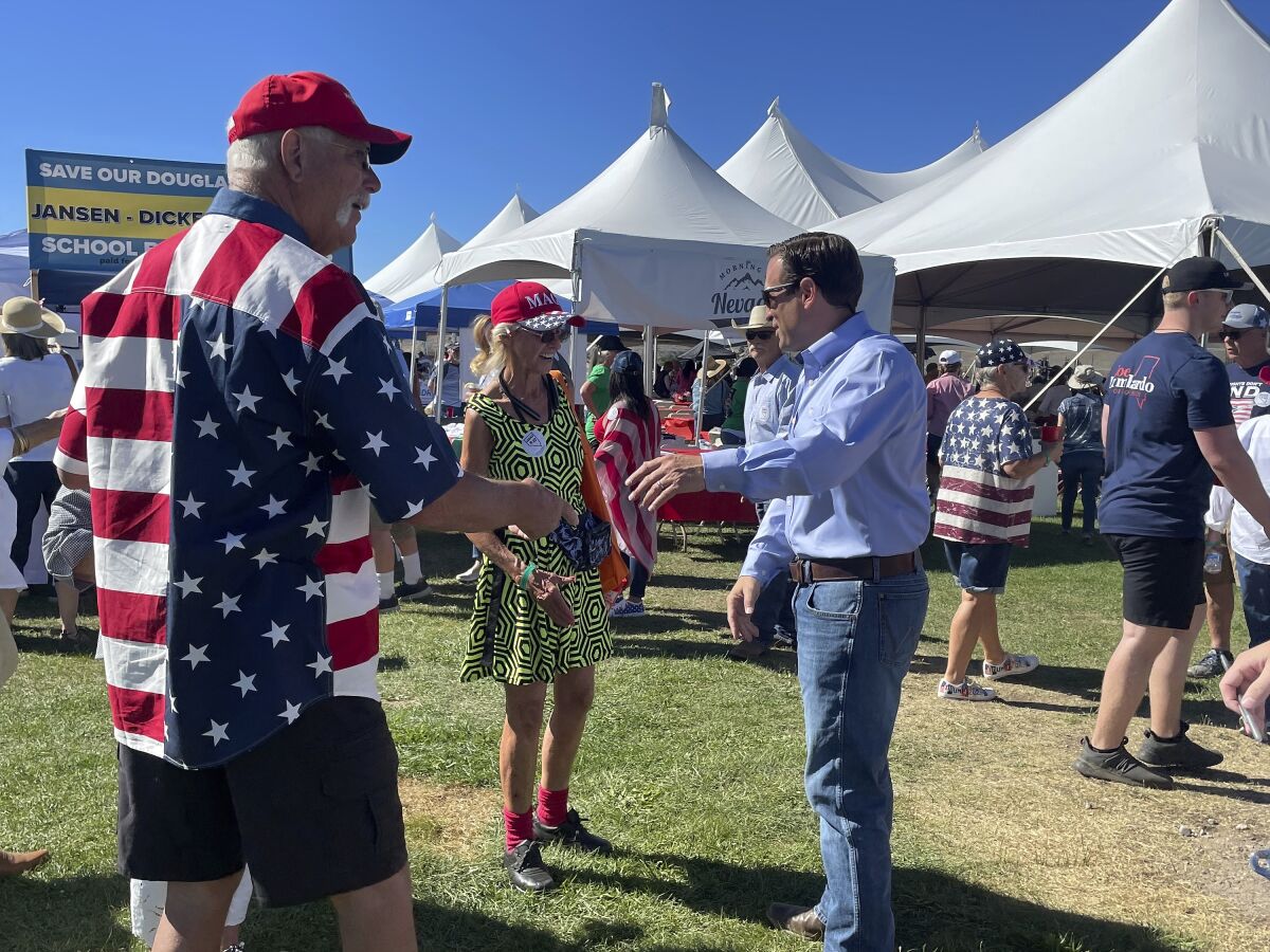 Republican Nevada Senate candidate Adam Laxalt, right, takes pictures with supporters at the seventh annual Basque Fry at the Corley Ranch on Saturday, Aug. 13, 2022, outside Gardnerville, Nev. (AP Photo/Gabe Stern)