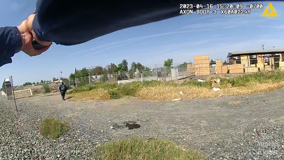 A body camera image shows an officer's hands raised with a gun as a man runs away.